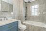 Bathroom with tile walls, tiled shower / bath, and vanity