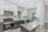 Kitchen featuring stainless steel appliances, light stone countertops, white cabinets, backsplash, and recessed lighting