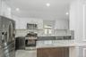 Kitchen with appliances with stainless steel finishes, white cabinetry, light stone counters, and recessed lighting