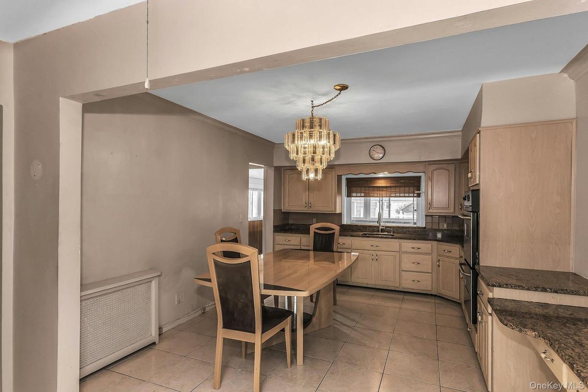 Kitchen featuring light wood-finish cabinetry, granite countertops, tile flooring, and a built-in double oven