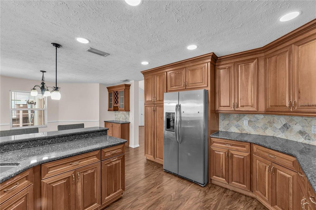 At the heart of the home, the spacious kitchen features custom wood cabinetry, Level 5 granite countertops, stone backsplash and stainless steel appli