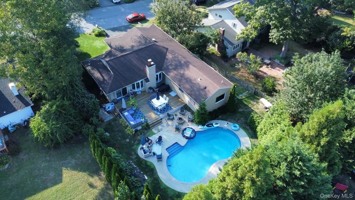 Expansive backyard featuring a custom-shaped swimming pool, a spacious wood deck, and mature perimeter landscaping