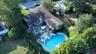 Expansive backyard featuring a custom-shaped swimming pool, a spacious wood deck, and mature perimeter landscaping
