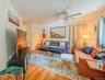 Upper Apartment  Living Room Hardwood-style flooring throughout, ceiling fan with integrated lighting, and multiple windows with vertical blinds