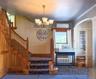 Grand Wood Staircase with carpeted and wood paneling, featuring a decorative chandelier and an arched doorway
