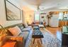 Upper Apartment  Living Room Hardwood-style flooring throughout, ceiling fan with integrated lighting, and multiple windows with vertical blinds  Livi