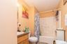 Bathroom featuring a wood-finish vanity with an integrated sink, a commode, and a shower-tub combination