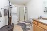 Compact bathroom featuring a shower stall with clear glass enclosure, a vanity with wood-finish cabinetry, a built-in sink, and a stacked washer and d