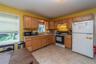 Kitchen featuring wood-finish cabinetry, laminate countertops, a built-in range with an overhead microwave, and resilient flooring