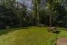 Expansive grassy area with mature trees and a wooded perimeter