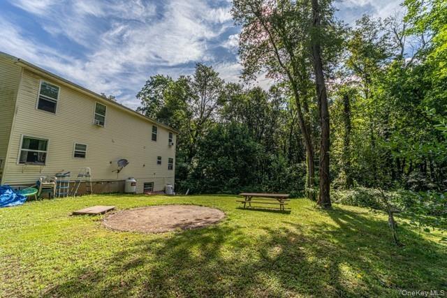 Expansive grassy yard with mature trees and a circular gravel patio area