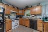 Kitchen featuring wood-finish cabinetry, a white gas range, and a black dishwasher