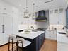 Kitchen with white cabinetry, charcoal island and gold pendants