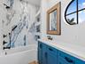 Bathroom with blue vanity and round window