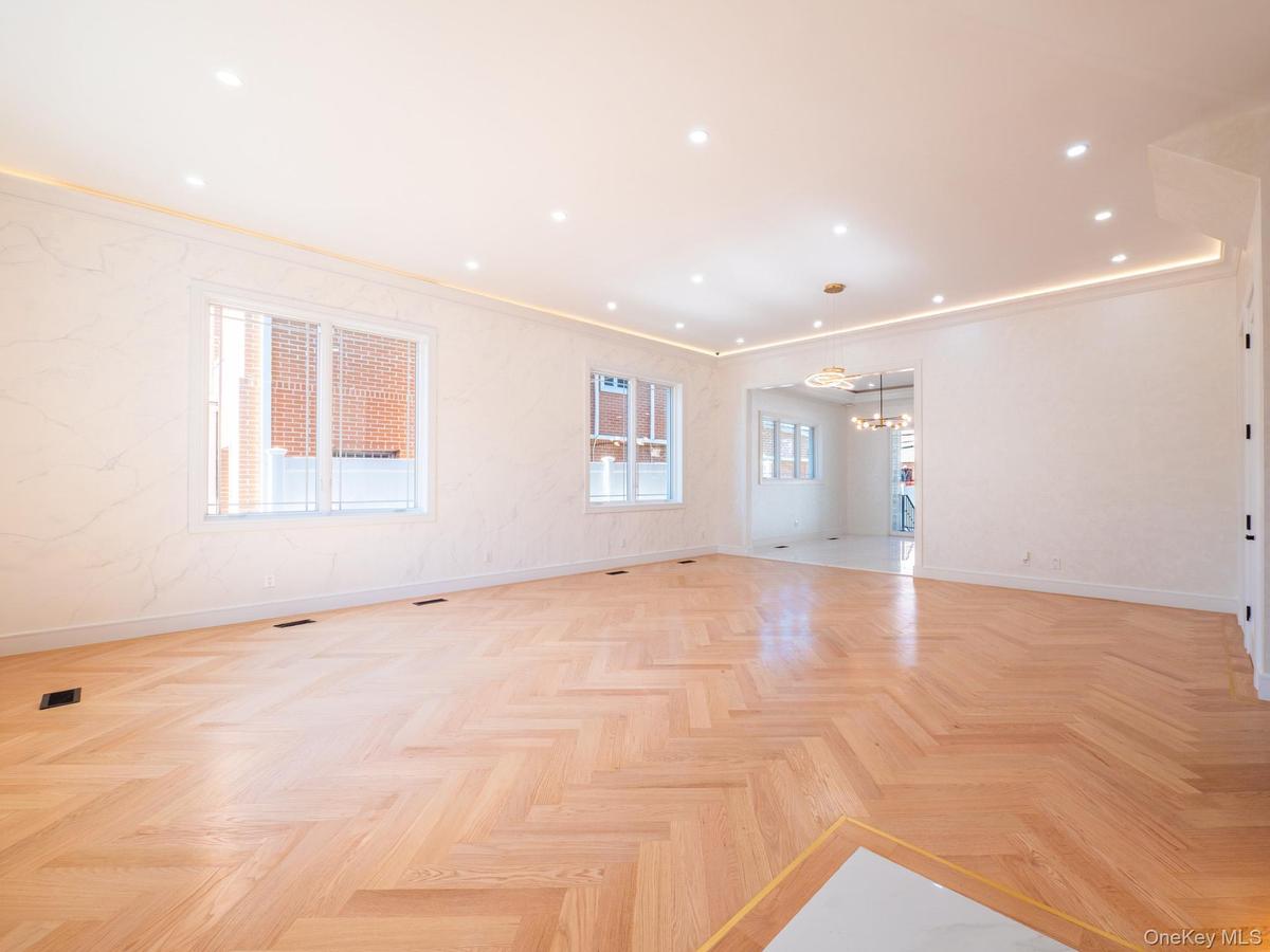 Herringbone pattern wood-finish flooring, recessed ceiling lighting, cove lighting, and multiple windows