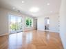 Herringbone wood-finish flooring, recessed ceiling lighting, a clear glass sliding door, and a white metal balcony railing