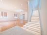 Herringbone wood-finish flooring, recessed ceiling lighting, cove lighting, marble-look tile entry, and illuminated staircase