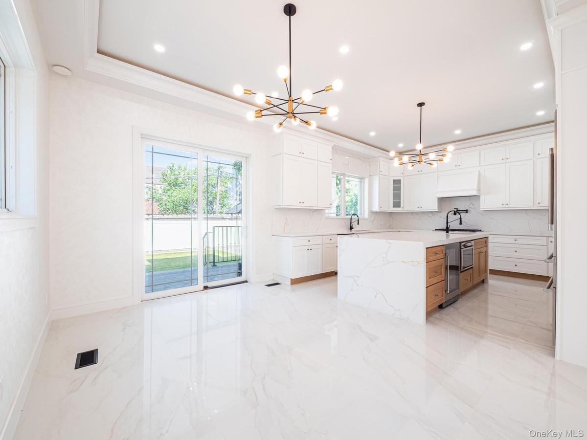 Modern kitchen featuring a large central island with integrated appliances and a waterfall countertop