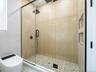 Glass-enclosed shower with a rainfall showerhead, pebble tile flooring, and integrated wall niches