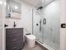 Modern bathroom featuring a glass-enclosed shower with matte black fixtures, a white tiled shower base, and a vanity with a white countertop