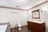 Dual vanity with wood-finish cabinetry, integrated sinks, and polished chrome fixtures