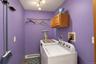 Laundry area with motion lighting, wall-mounted cabinetry, and a metal hanging rod