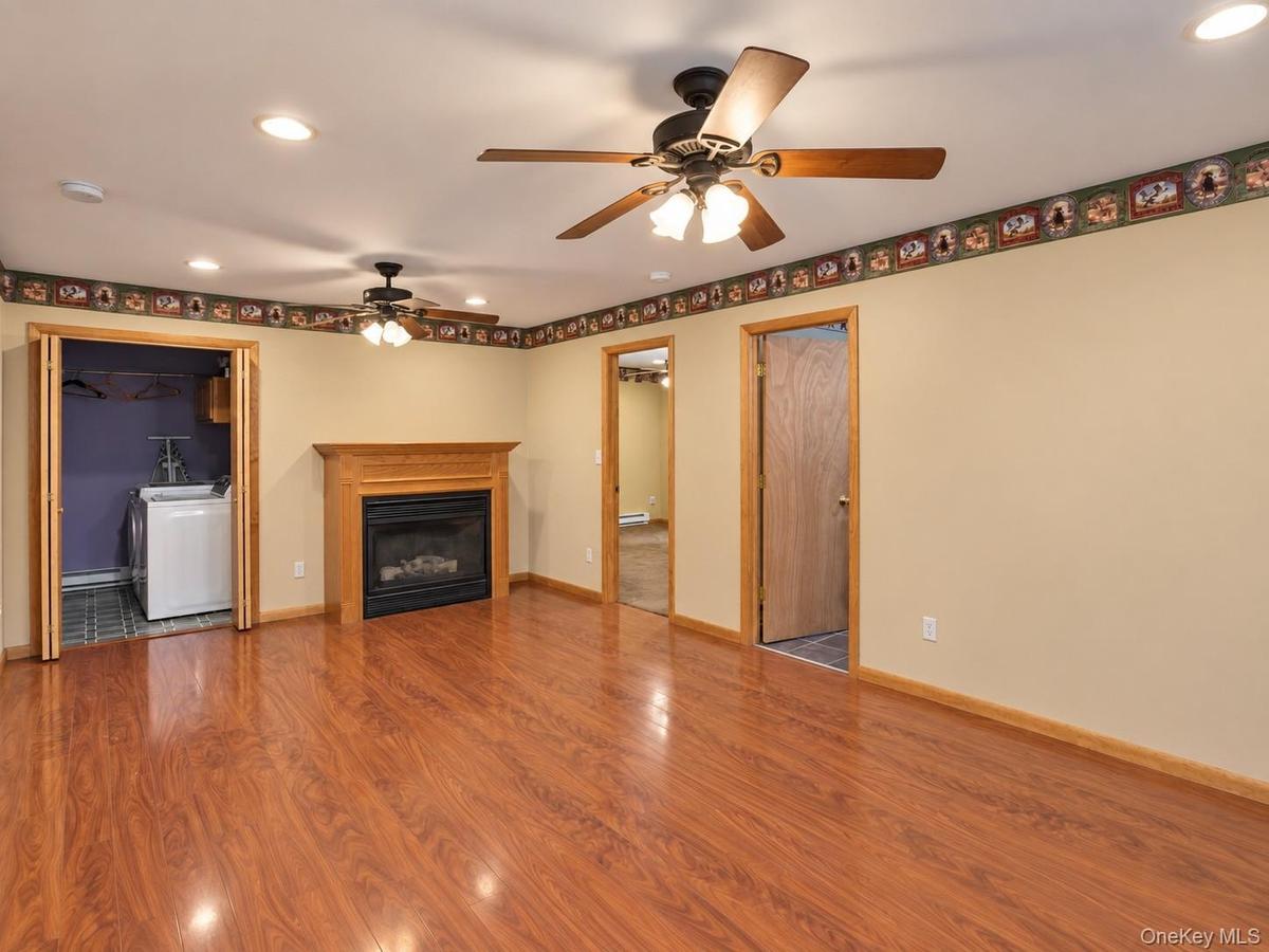 Wood-finish flooring, recessed lighting, ceiling fans, and a propane fireplace with a wood-finish mantel