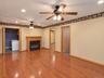 Wood-finish flooring, recessed lighting, ceiling fans, and a propane fireplace with a wood-finish mantel