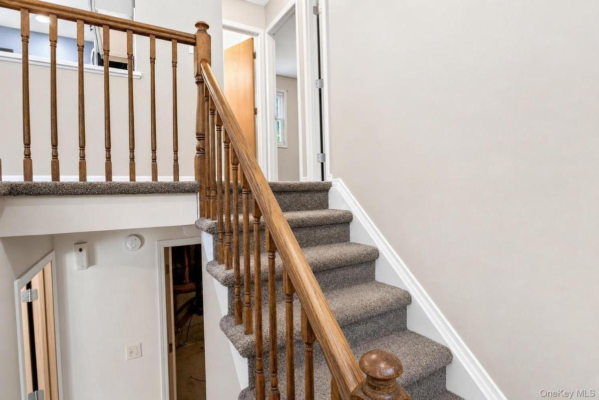 Carpeted staircase with wood-finish balusters and handrail