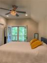 Cottage bedroom with vaulted ceiling with recessed lighting, a decorative ceiling fan, and French doors that leads to private  deck