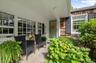 Stone patio with a covered entry, multiple multi-pane windows, and natural wood-shingle siding
