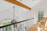 Hallway with healthy amount of natural light, high vaulted ceiling, light wood-style flooring, and a chandelier