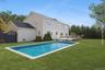 Outdoor pool with a lawn, a wooden deck, and a gate