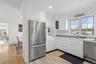 Kitchen featuring appliances with stainless steel finishes, ornamental molding, white cabinets, wood finish floors, and backsplash