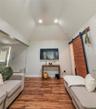 Cottage living room with vaulted ceiling with recessed lighting, wood-finish flooring, and a sliding wood barn door