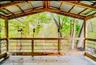 Cottage covered private deck with a corrugated metal roof, wood-finish flooring, and wood railings with black metal balusters