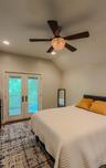 Cottage bedroom with vaulted ceiling with recessed lighting, a decorative ceiling fan, and French doors that leads to private  deck
