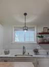 Cottage kitchen featuring a central island with white shaker cabinetry, stainless steel appliances, and open wood shelving