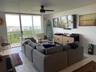 Sliding glass doors opening to a balcony, white tongue-and-groove ceiling, ceiling fan with integrated lighting, wall-mounted media console, and white
