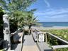 Beachfront access with a wooden boardwalk, mature palm trees, and ocean scenery