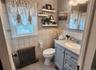 Bathroom featuring a window, pedestal sink with vanity, wall-mounted mirror, and tiled walls