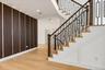 Hardwood flooring, custom wall paneling with integrated lighting, recessed ceiling lighting, staircase with decorative metal balusters, and a rich woo