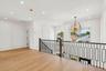Hardwood flooring, contemporary chandelier, recessed lighting, white paneled walls, and dark metal stair railing with wood newel posts