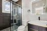Contemporary bathroom featuring a sliding glass shower door, a large rectangular illuminated mirror, a vessel sink, dark wood-finish cabinetry, and a 