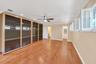 Hardwood flooring, recessed lighting, ceiling fan, crown molding, and built-in cabinetry with glass panel doors