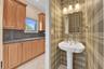 Powder room, guest bath with pedestal sink, polished chrome fixtures, plaid wall covering, and a tri-light vanity fixture.
