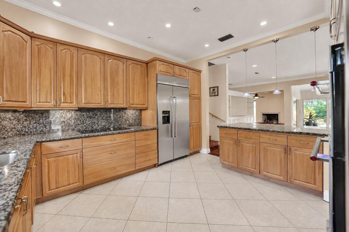 Ceramic tile flooring, light wood-finish cabinetry, stainless steel refrigerator, granite countertops, and recessed lighting. Wall color has been virt