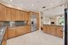 Ceramic tile flooring, light wood-finish cabinetry, stainless steel refrigerator, granite countertops, and recessed lighting. Wall color has been virt