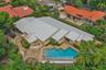 Expansive residence featuring a multi-gabled roofline, a geometric-shaped swimming pool, and extensive stone hardscaping