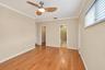 Wood-finish flooring with neutral wall tones, crown molding, and a ceiling fan with integrated lighting